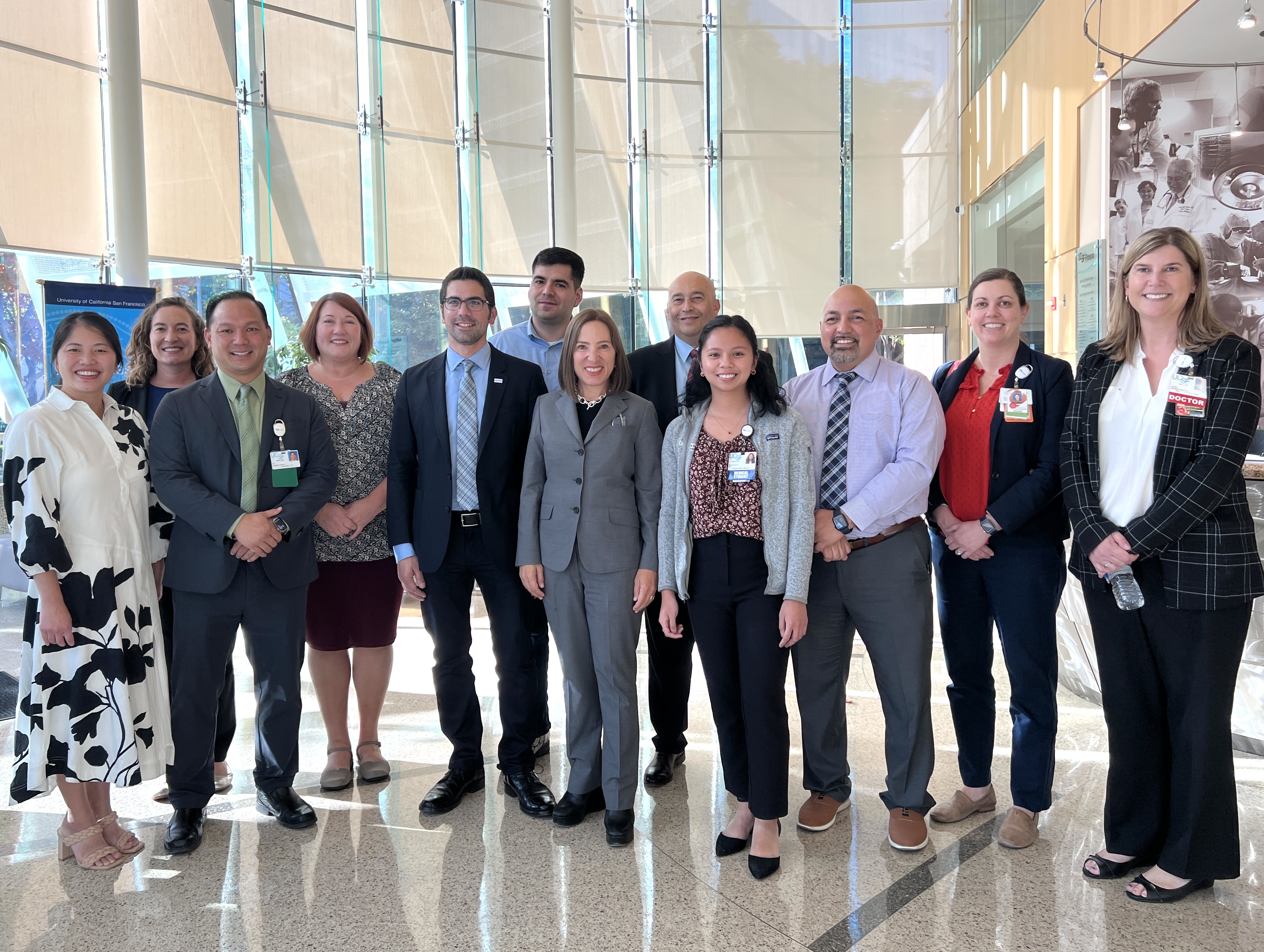 Group of twelve people standing in UCSF Fresno lobby posing for a picture