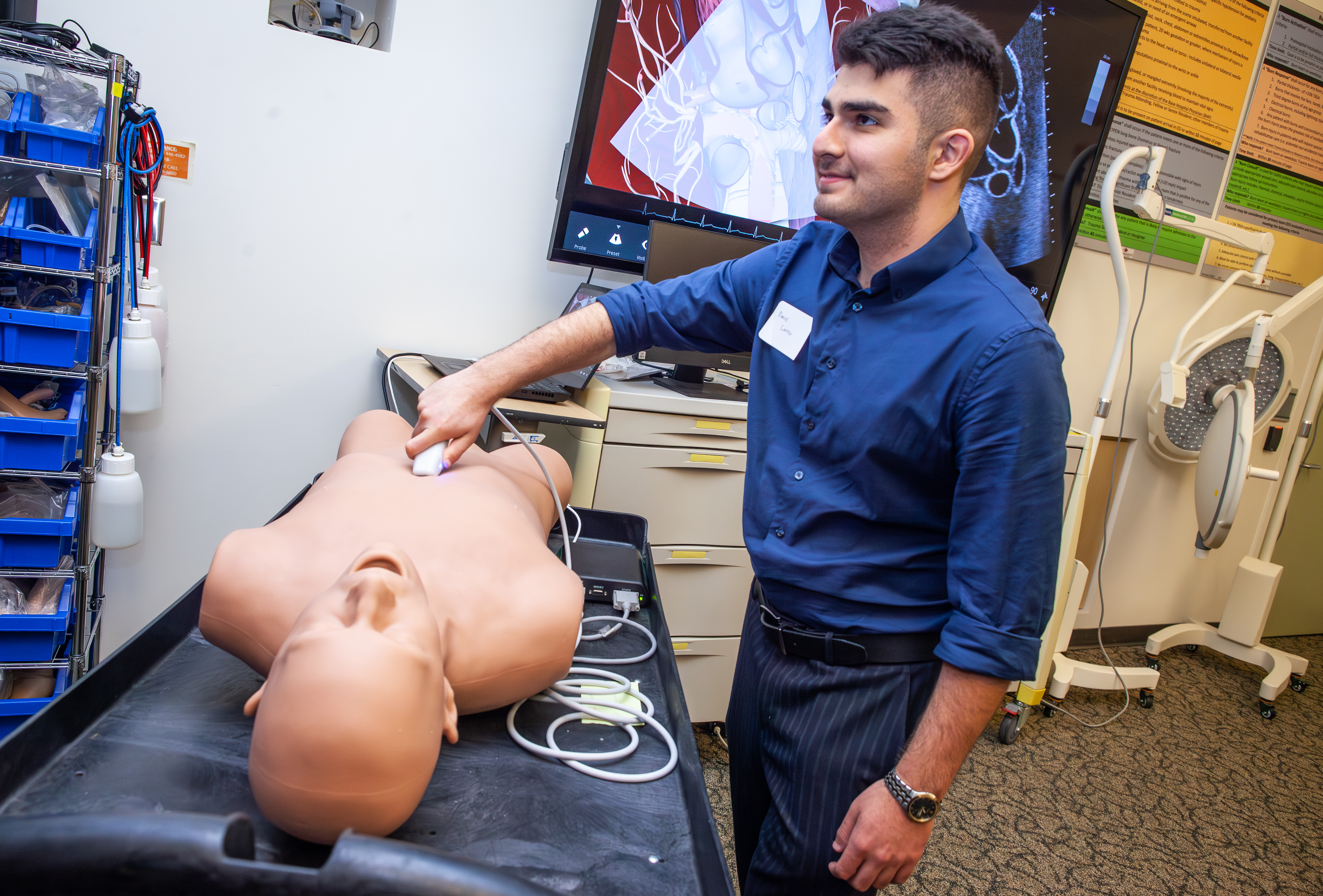 Male medical student standing next to a medical dummy.