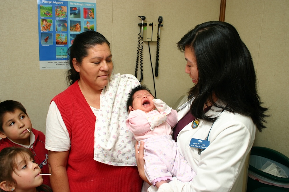 a member of UCSF Fresno faculty tenderly holds a crying baby as the baby's family looks on